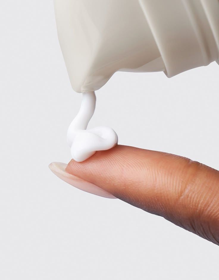 White Cleanser being pumped from bottle onto finger with grey background