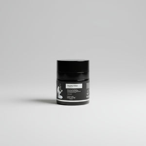Black airless jar with black and silver 
label on a gray background