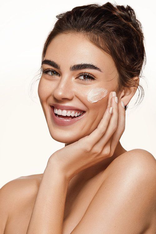 Woman applying cream to her face with a white background